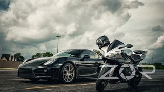 Black Porsche Cayman parked beside a sport motorcycle under storm clouds