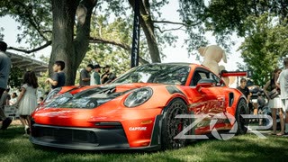 Orange Porsche 911 GT3 RS parked under trees at a car show