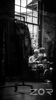 Tailor at work by a window in a workshop, in black and white