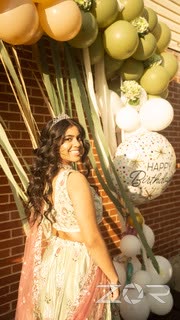 Young woman in a lehenga posing under a birthday balloon arch