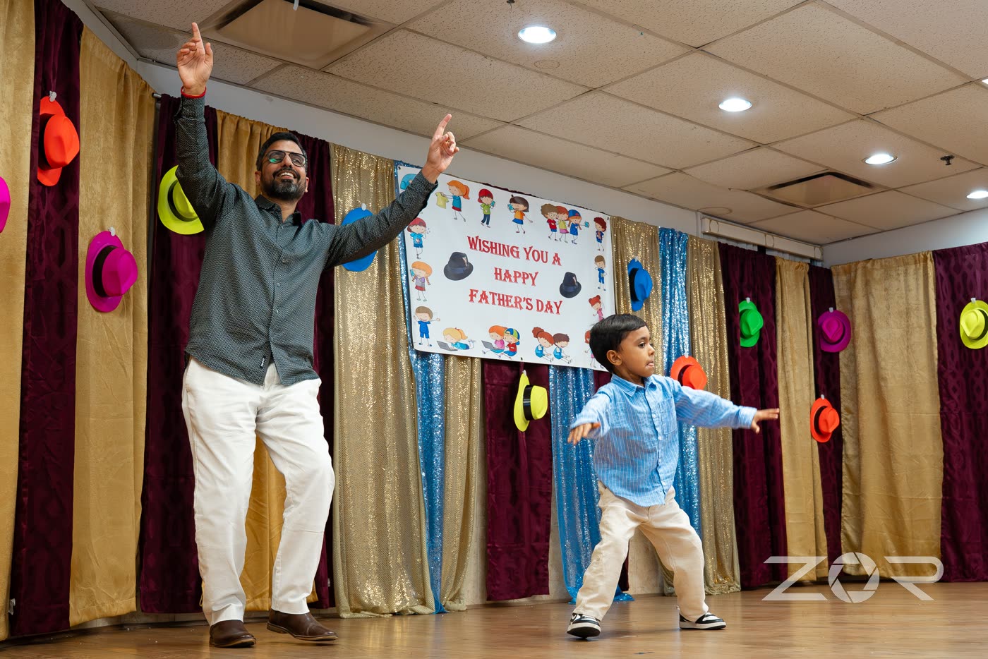 A father and his young son dancing on stage at a Father's Day event