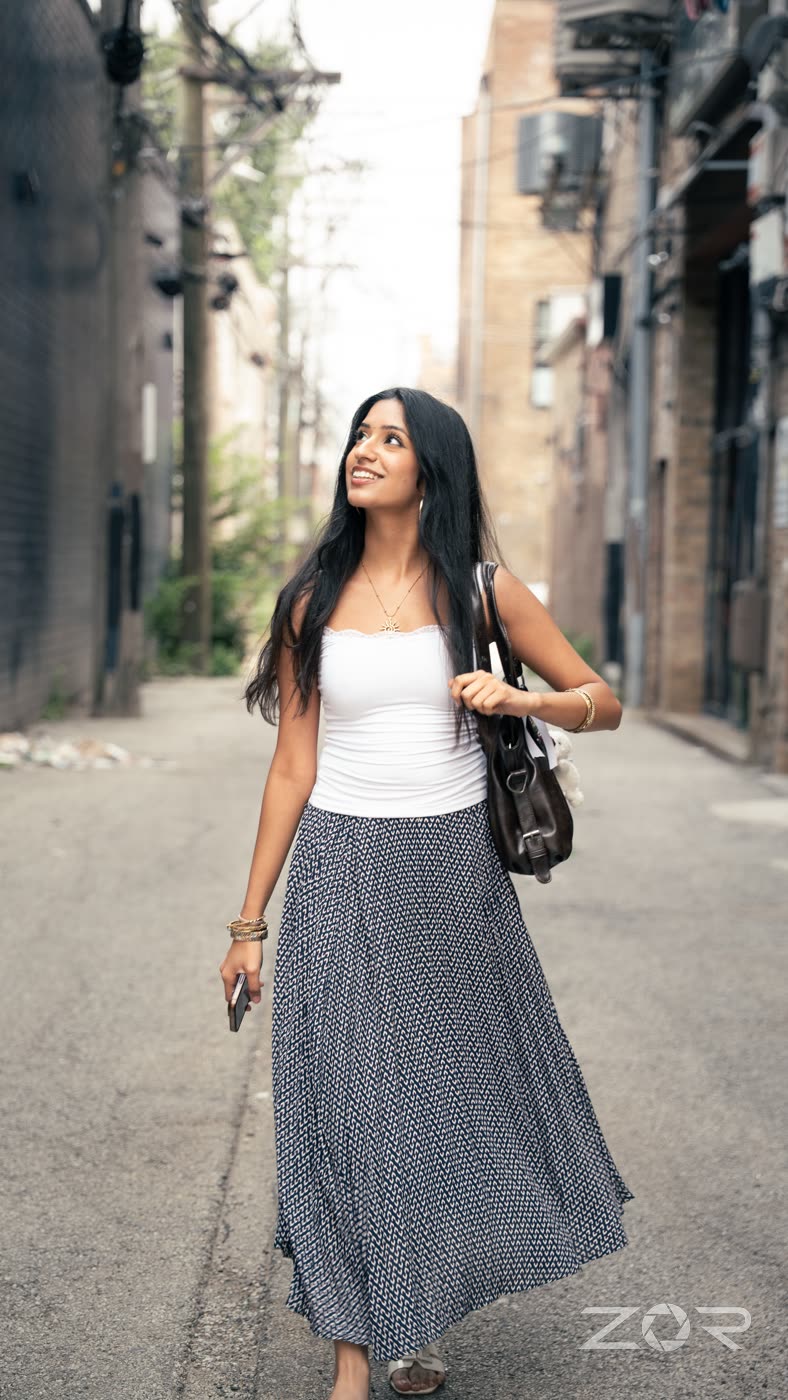 Woman walking through a city alley in a white top and patterned skirt