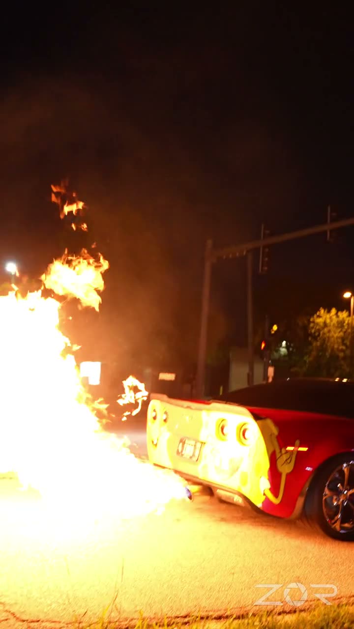 Red sports car shooting flames from its exhaust at night